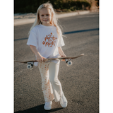 Girl walking and holding a skateboard whilst wearing Sun Dance Flares and Tee